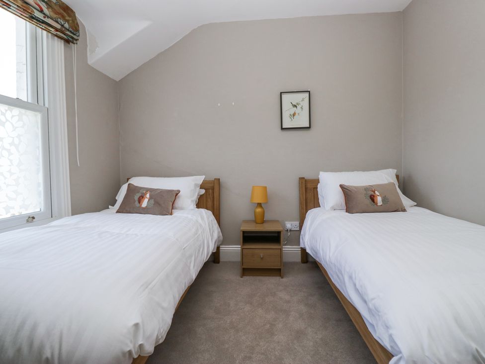 A bedroom with two single beds a nightstand with a lamp and a framed picture on the wall at Sunnycroft in Keswick