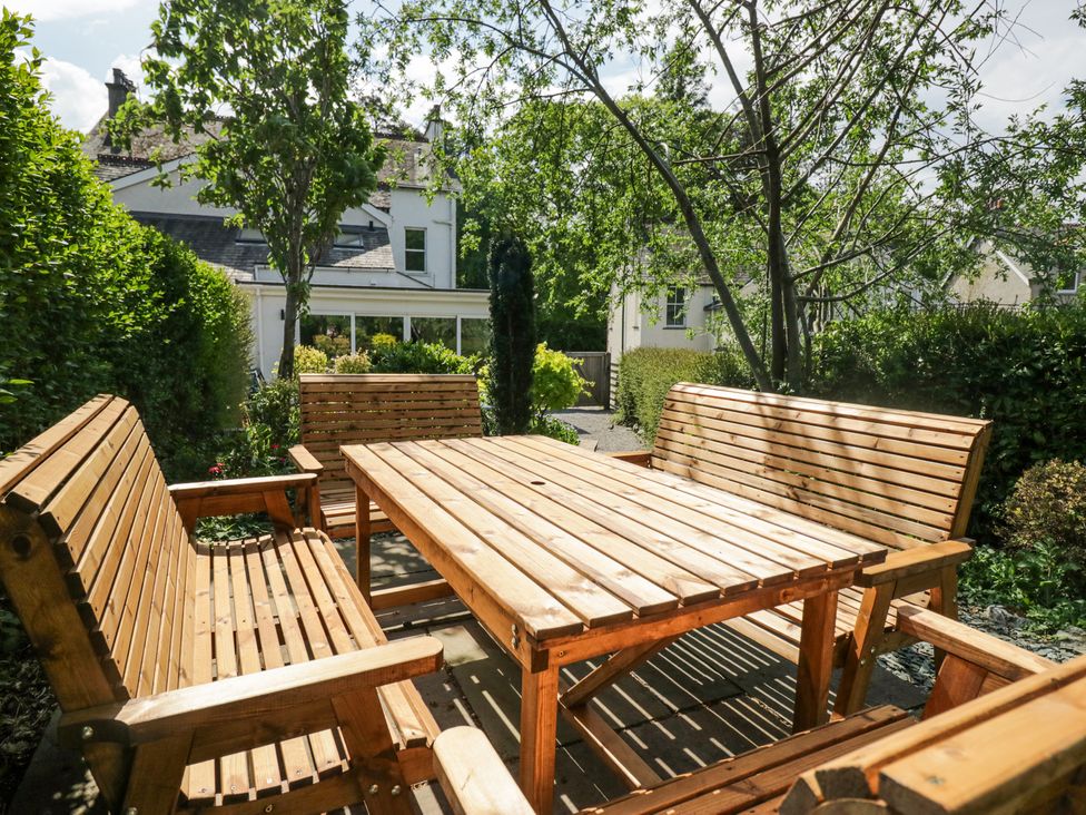 An outdoor seating area with wooden benches and a table in a garden at Sunnycroft in Keswick