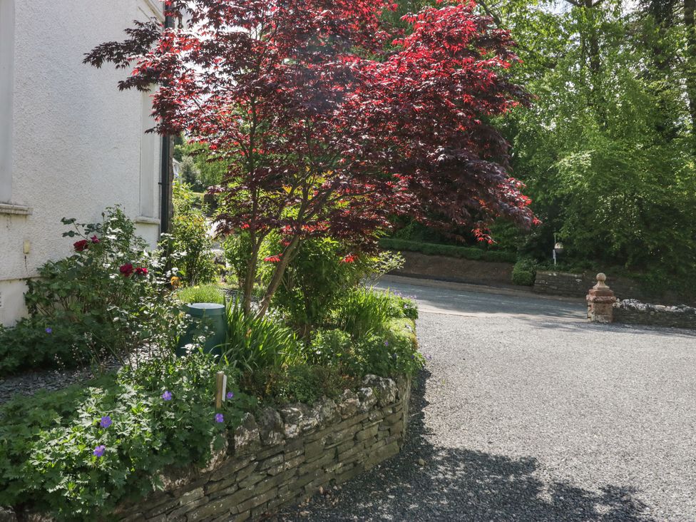 A garden with a red-leaved tree and flower bed beside a gravel driveway at Sunnycroft in Keswick