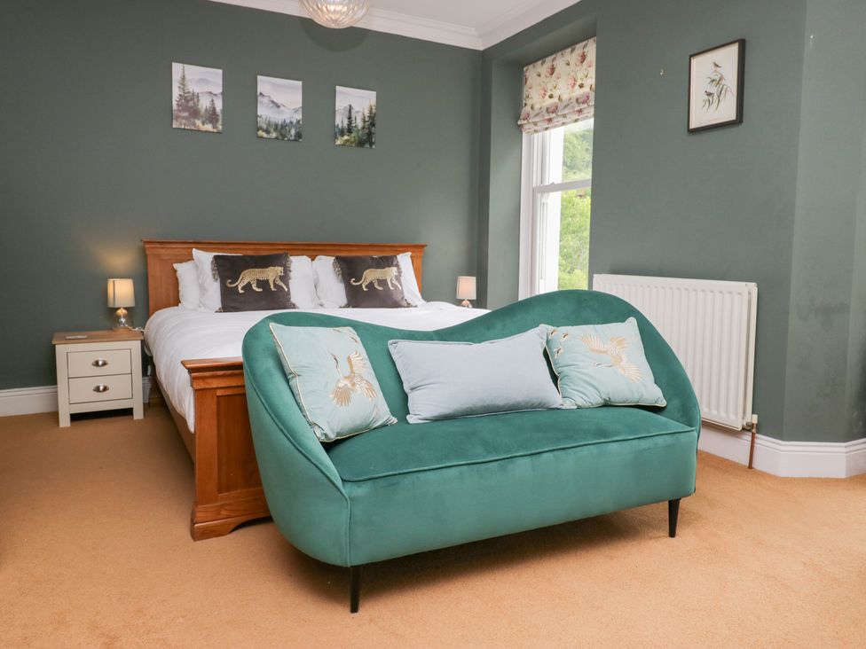 A bedroom with a bed and a green sofa at Sunnycroft in Keswick