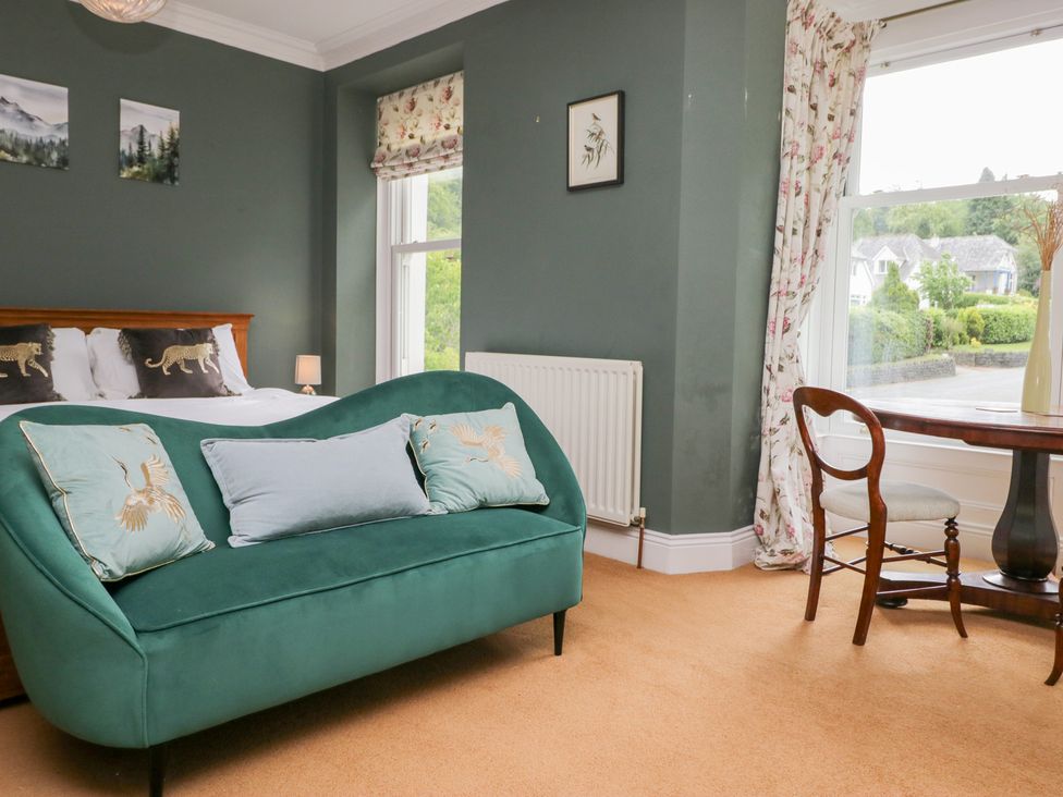 A bedroom with a green sofa and a table at Sunnycroft in Keswick