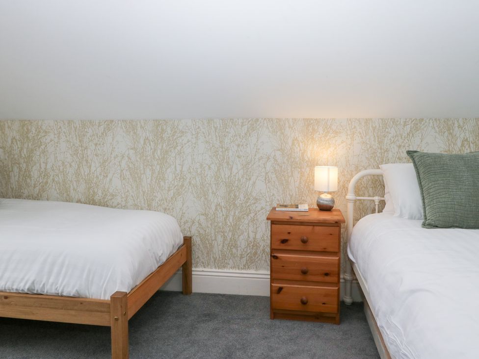 A bedroom with two beds and a bedside table at Sunnycroft in Keswick
