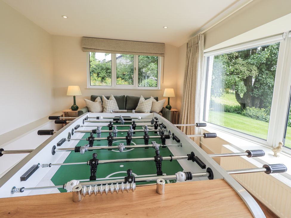 A foosball table with a sofa and window at Rowanhill in Kendal