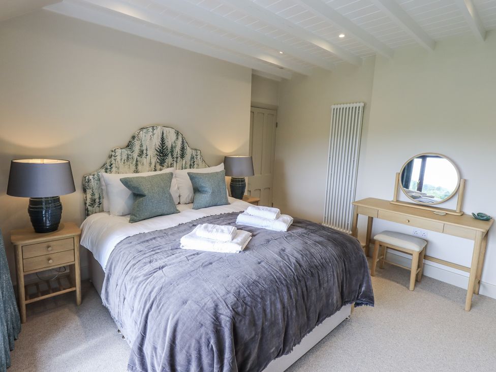 A bedroom with a bed and mirror at Rowanhill in Kendal