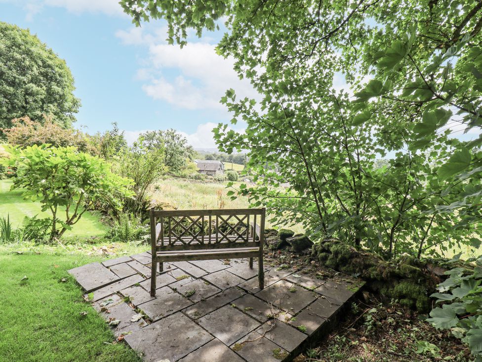 A garden with a stone patio and bench at Rowanhill, Kendal