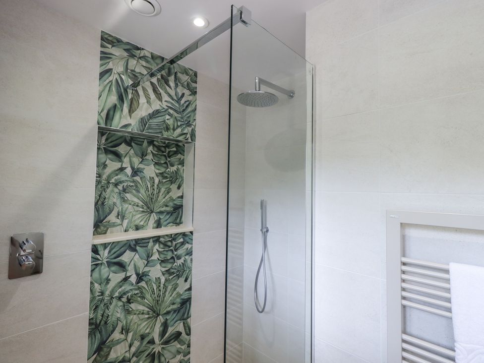 A shower with glass door and wall tiles at Rowanhill in Crook near Staveley