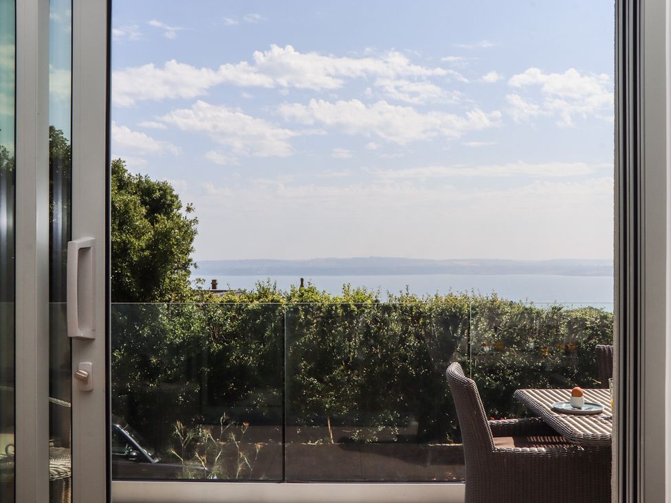 A view of the sea from a window with a table and chairs at Seacroft in Torquay