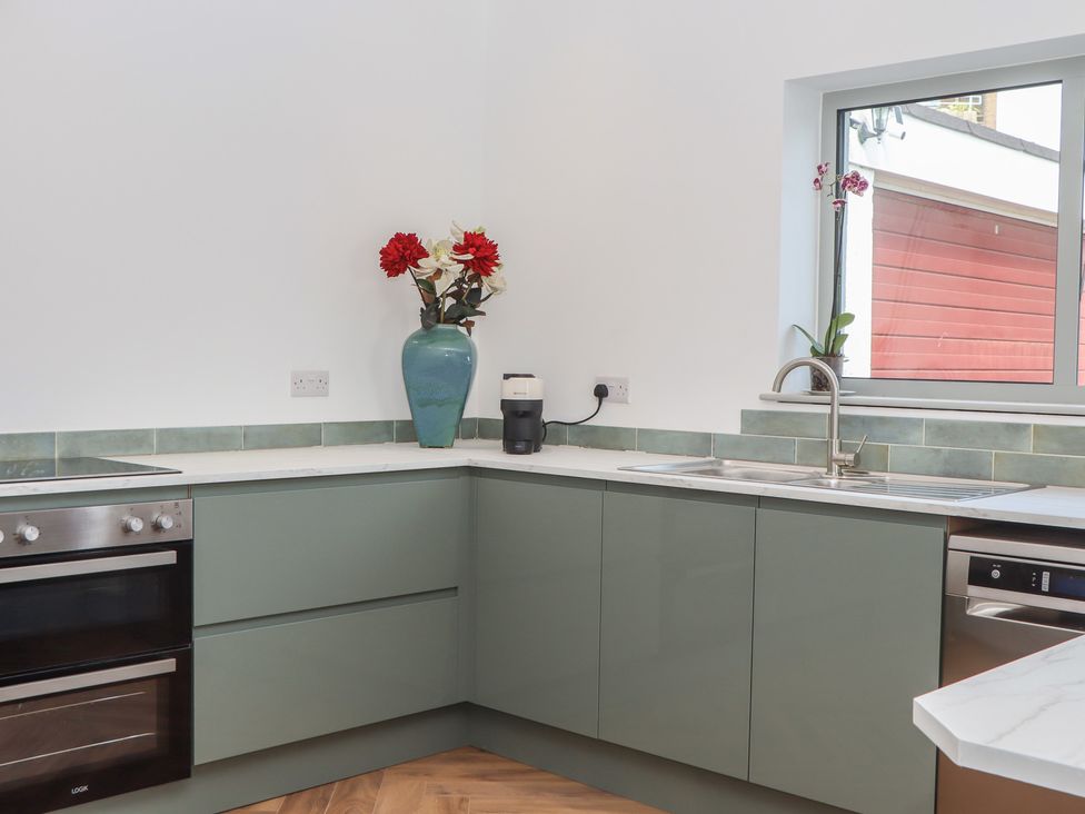A kitchen with cabinets, sink, and decorative vase at Seacroft in Torquay
