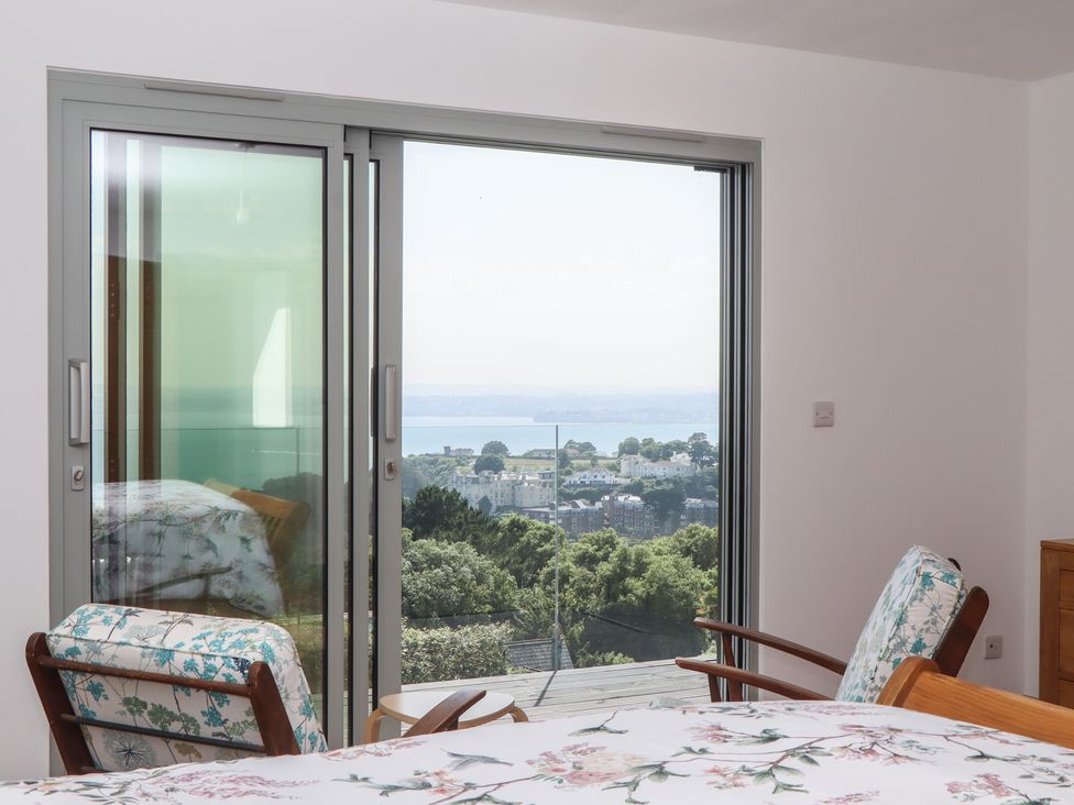 A bedroom with a bed and chairs overlooking a view at Seacroft in Torquay
