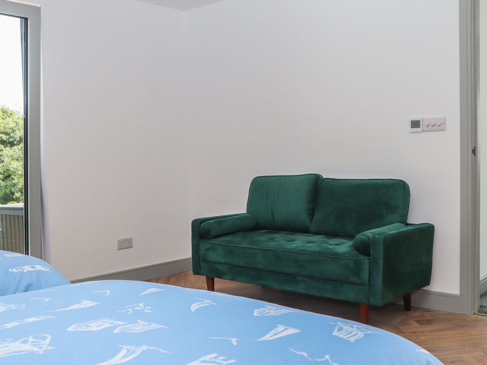 A bedroom with a green sofa and blue bed linens at Seacroft in Torquay