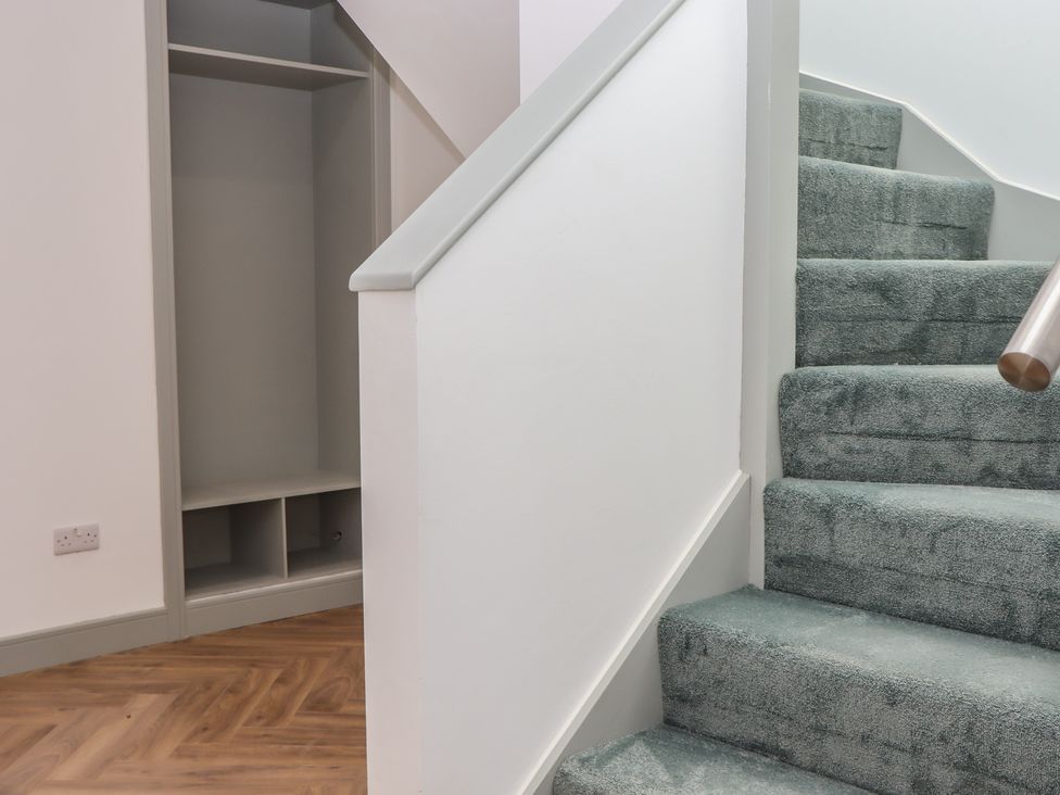 A hallway with a staircase and cupboard at Seacroft in Torquay