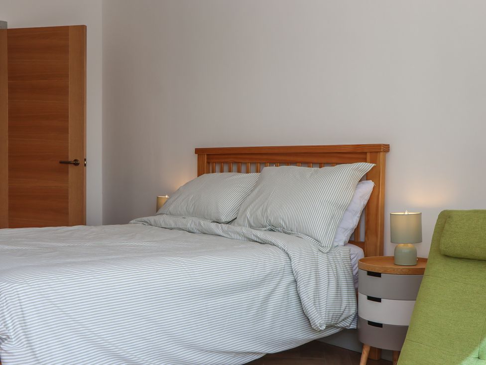 A bedroom with a bed, nightstand, and lamp at Seacroft in Torquay