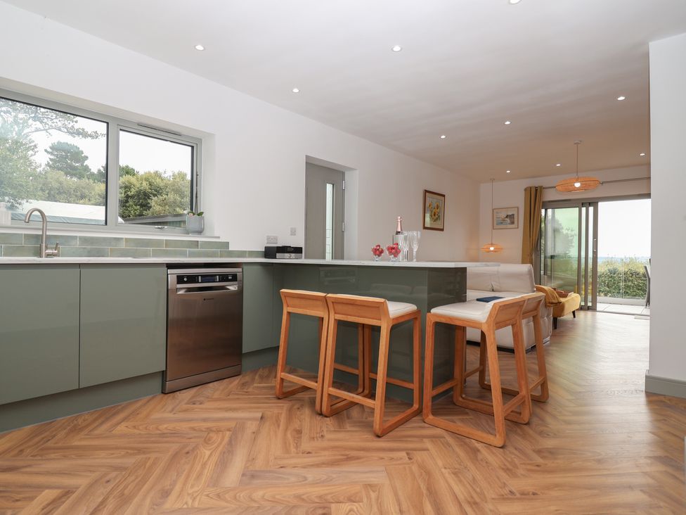 A kitchen with bar stools and sliding doors at Seacroft in Wellswood near Torquay