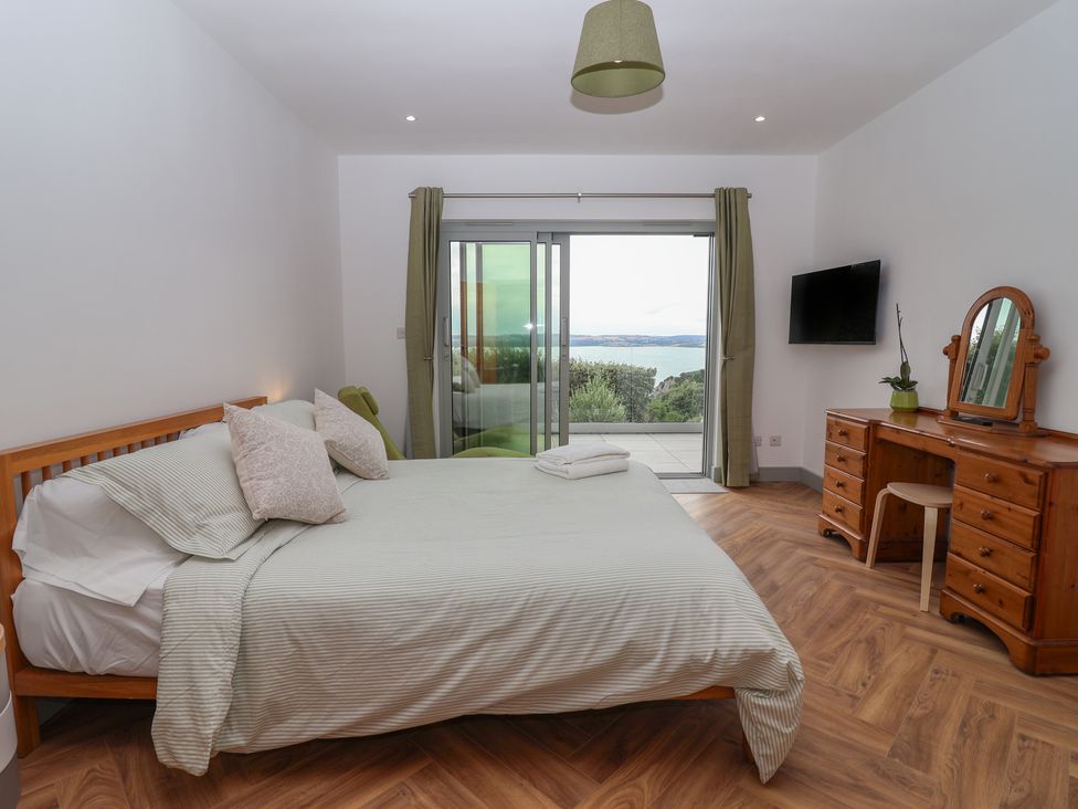 A bedroom with a bed and dresser at Seacroft in Wellswood near Torquay