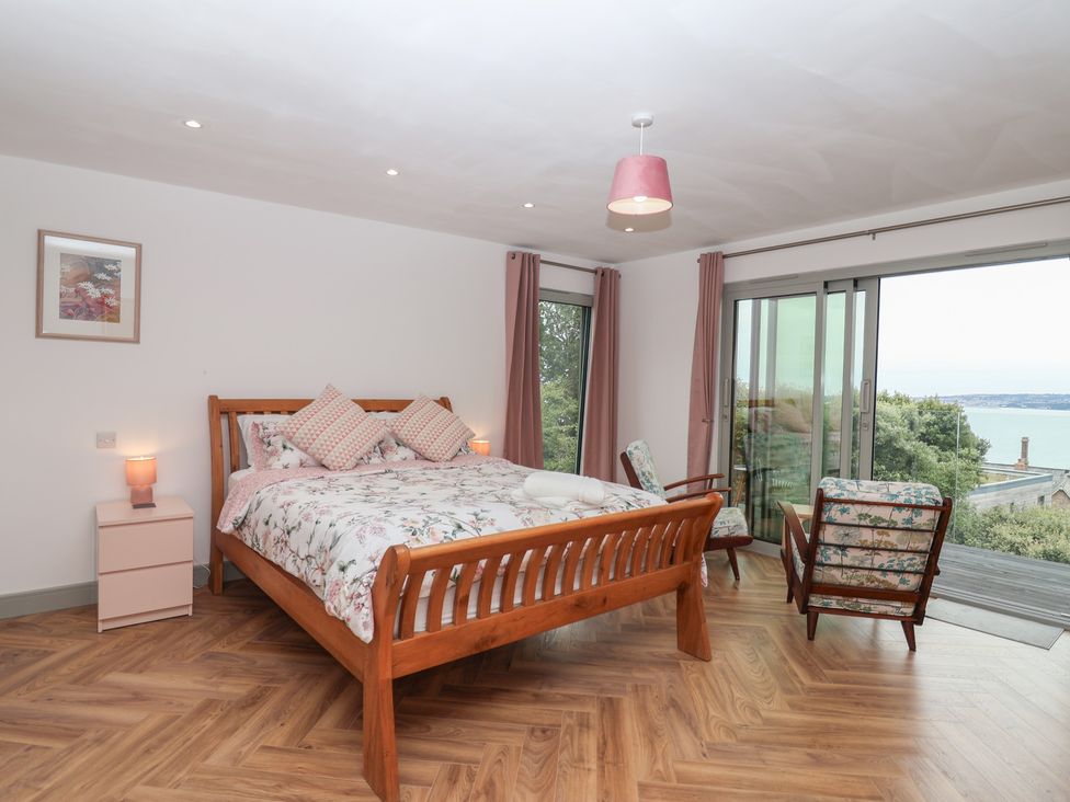 A bedroom with a bed and chairs at Seacroft in Wellswood near Torquay