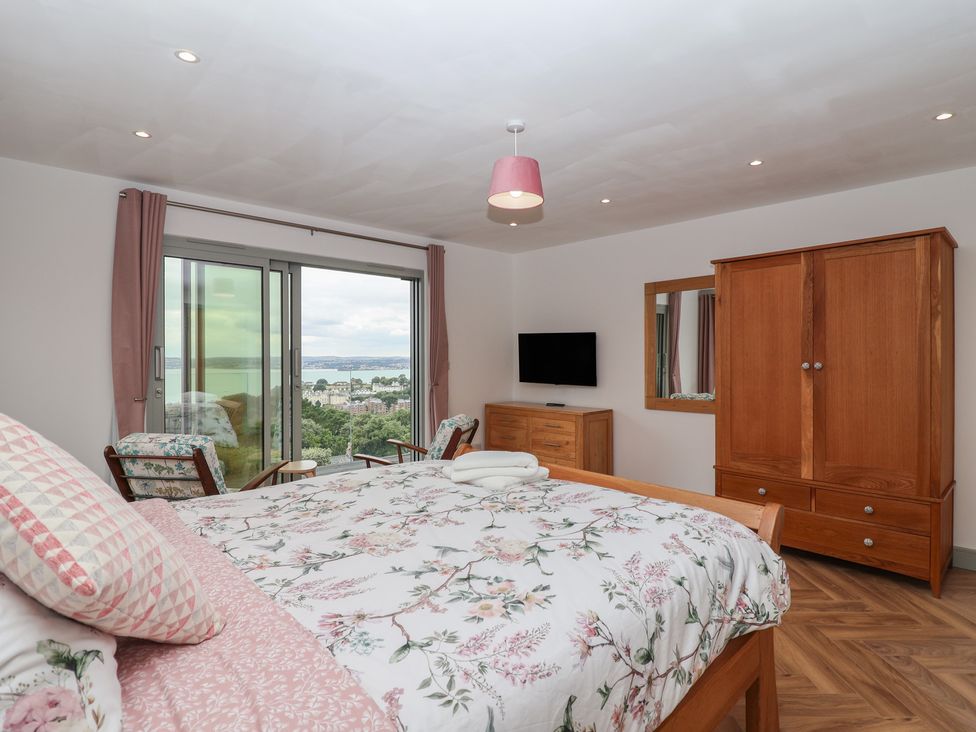 A bedroom with a bed and wardrobe at Seacroft in Wellswood near Torquay
