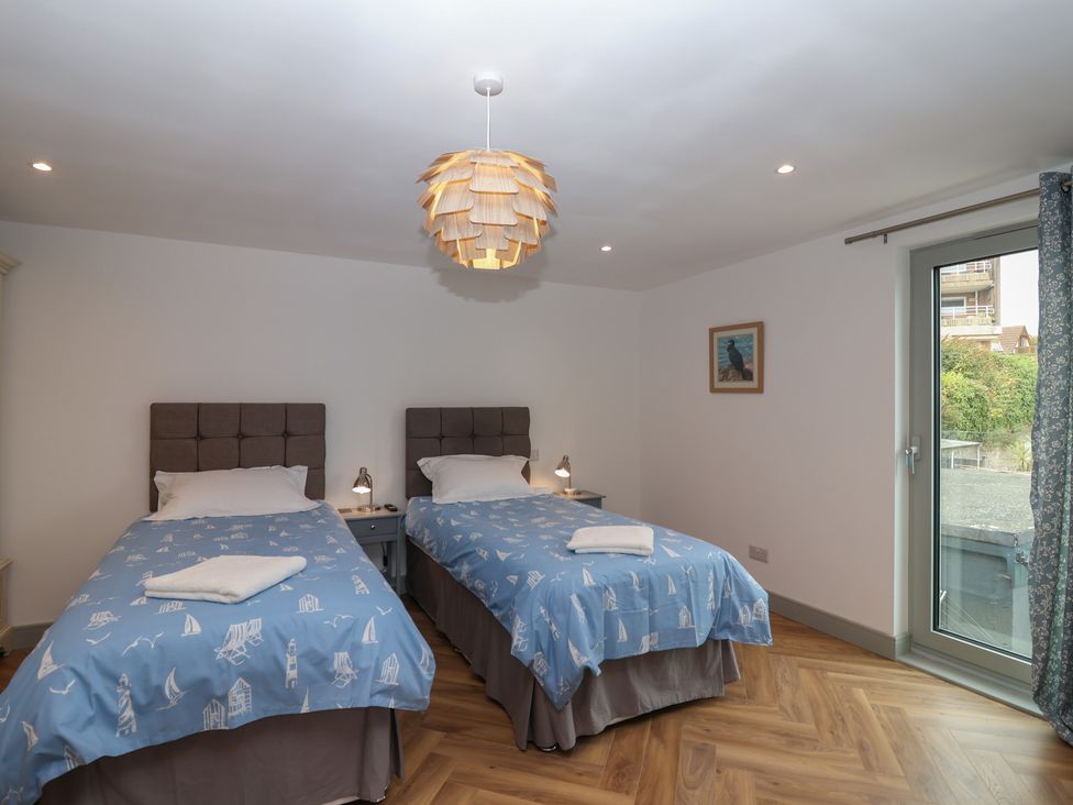 A bedroom with two single beds and a door leading outside at Seacroft in Wellswood near Torquay