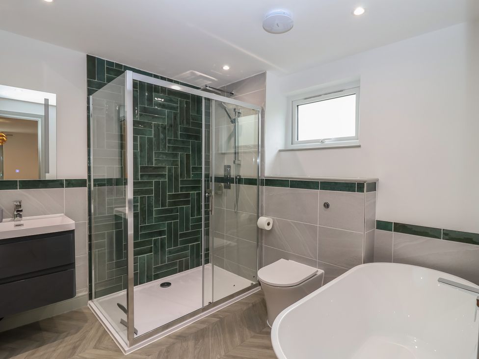 A bathroom with a shower, bathtub, and toilet at Seacroft in Wellswood near Torquay