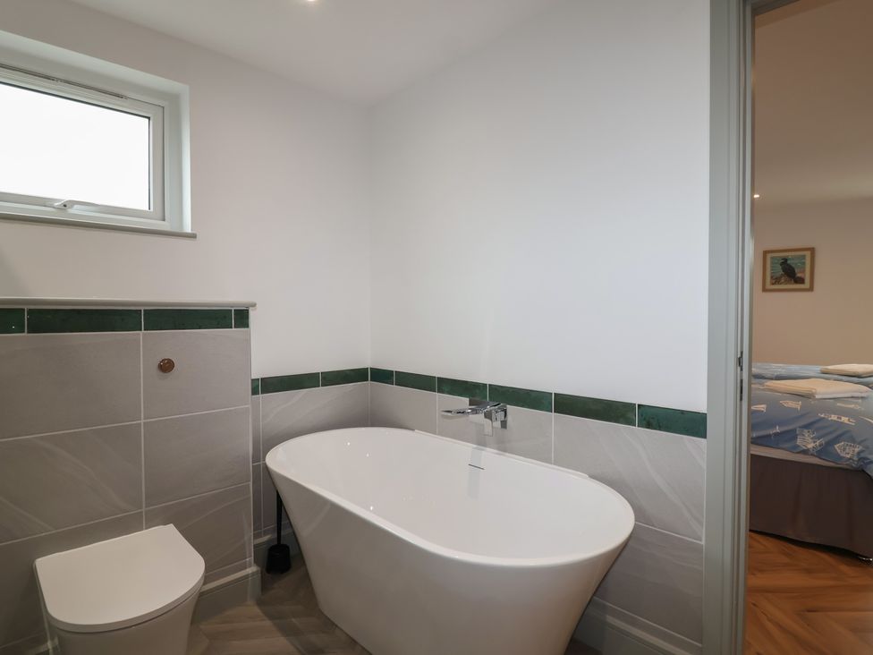 A bathroom with a bathtub and a toilet at Seacroft in Wellswood near Torquay