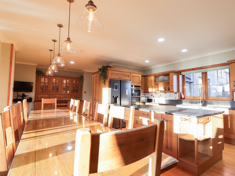 A kitchen with a long table and wooden chairs at Northbanks House in Thurso
