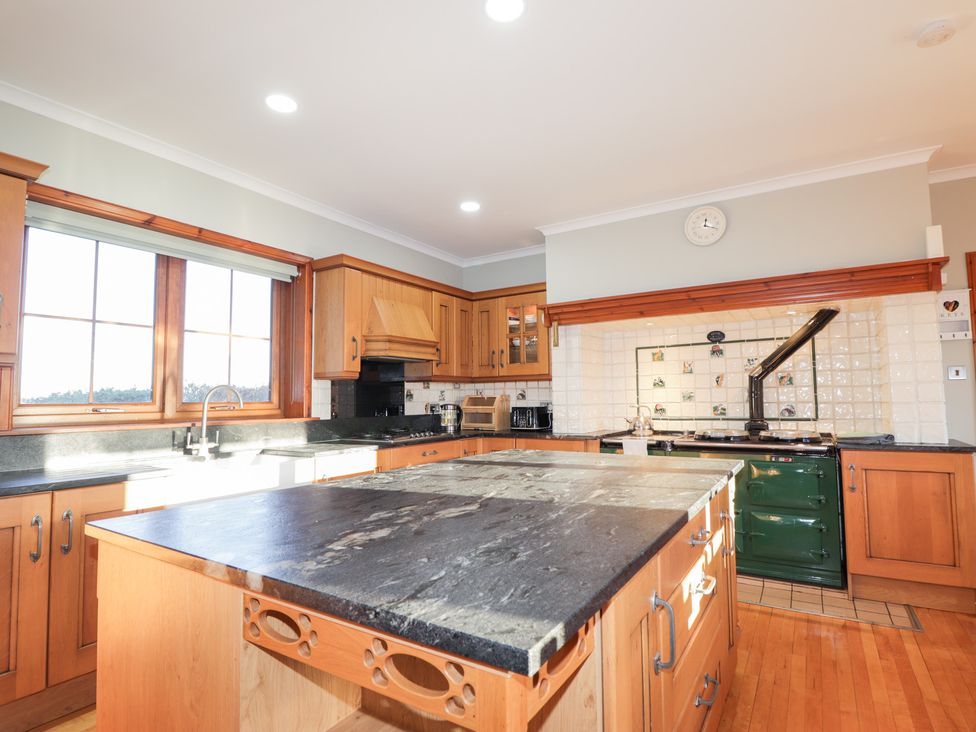 A kitchen with wooden cabinets and a black countertop at Northbanks House Thurso