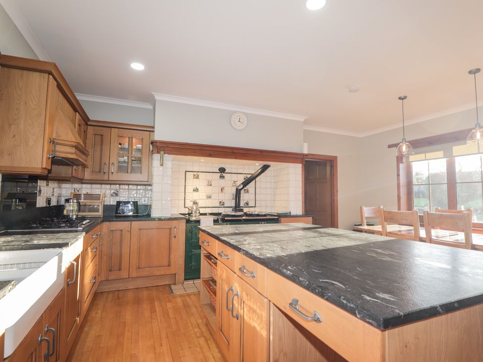 A kitchen with wooden cabinetry and black countertop at Northbanks House in Thurso