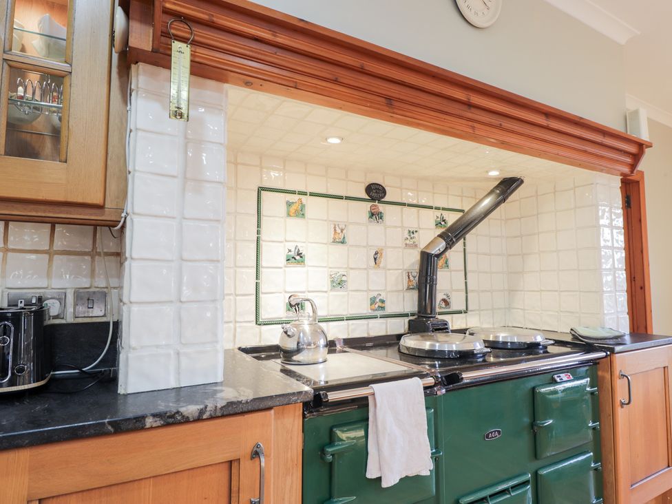 A kitchen featuring a stove, kettle, and tiled wall at Northbanks House Thurso