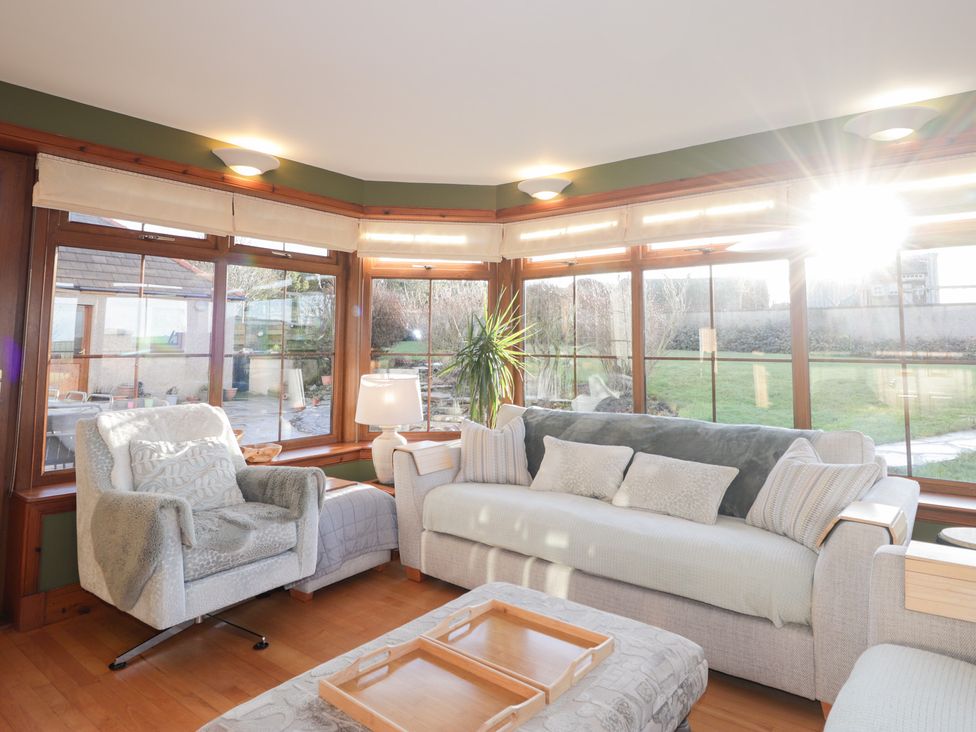 A sunroom with seating and large windows at Northbanks House Thurso