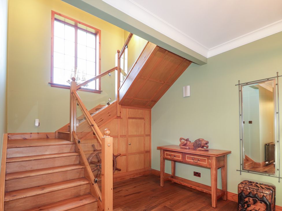 A hallway with a staircase and a console table at Northbanks House in Thurso
