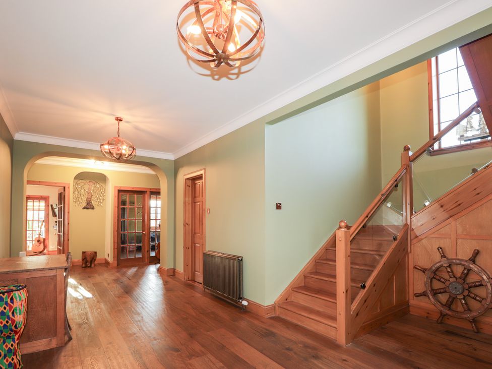 A hallway with a staircase and light fixtures at Northbanks House Thurso