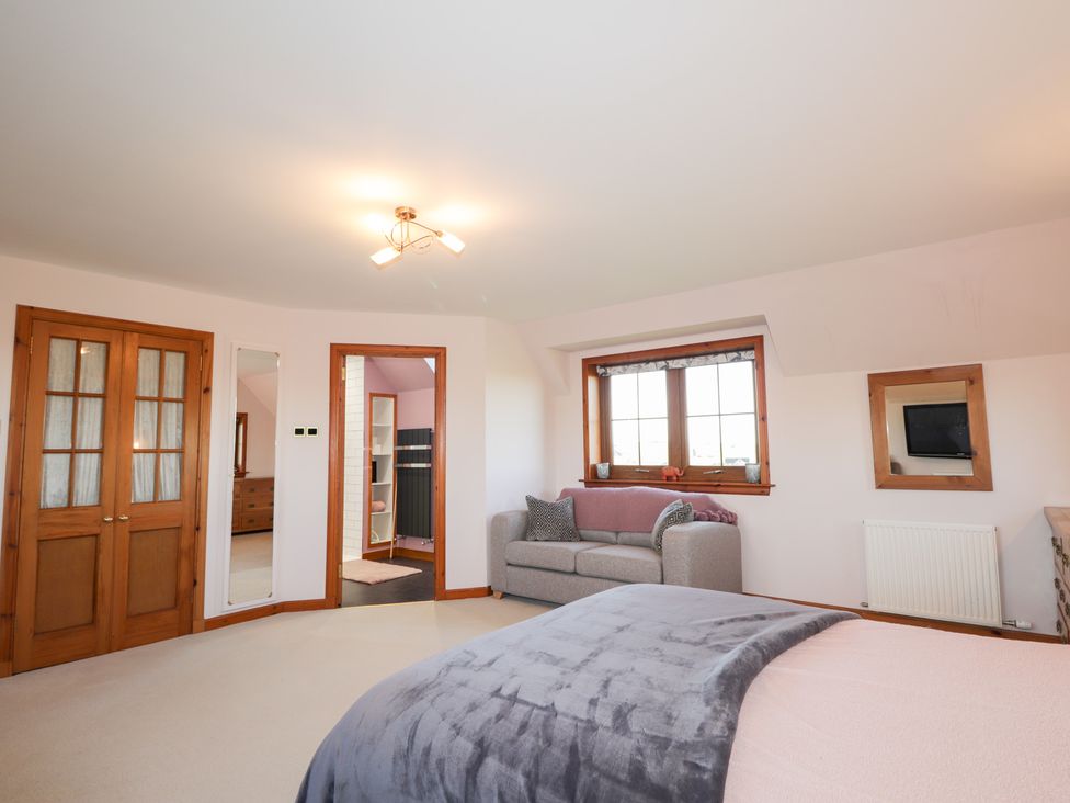 A bedroom with a bed, sofa, and windows at Northbanks House Thurso
