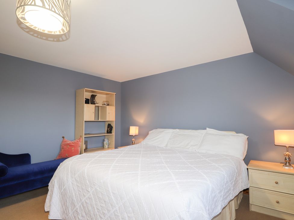 A bedroom with a bed, nightstand, and bookshelf at Northbanks House Thurso