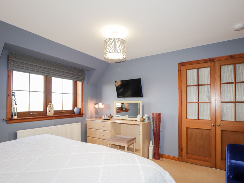 A bedroom with a bed, dresser, television, and window at Northbanks House in Thurso