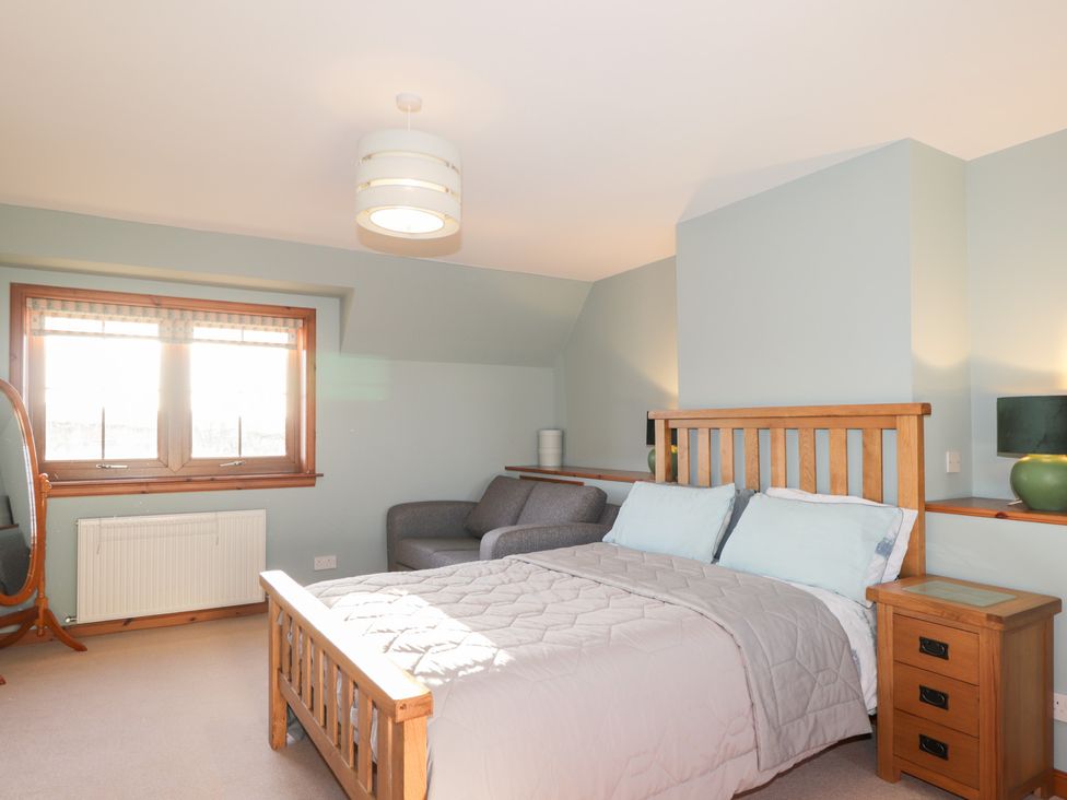 A bedroom with a bed, sofa, and lamp at Northbanks House in Thurso