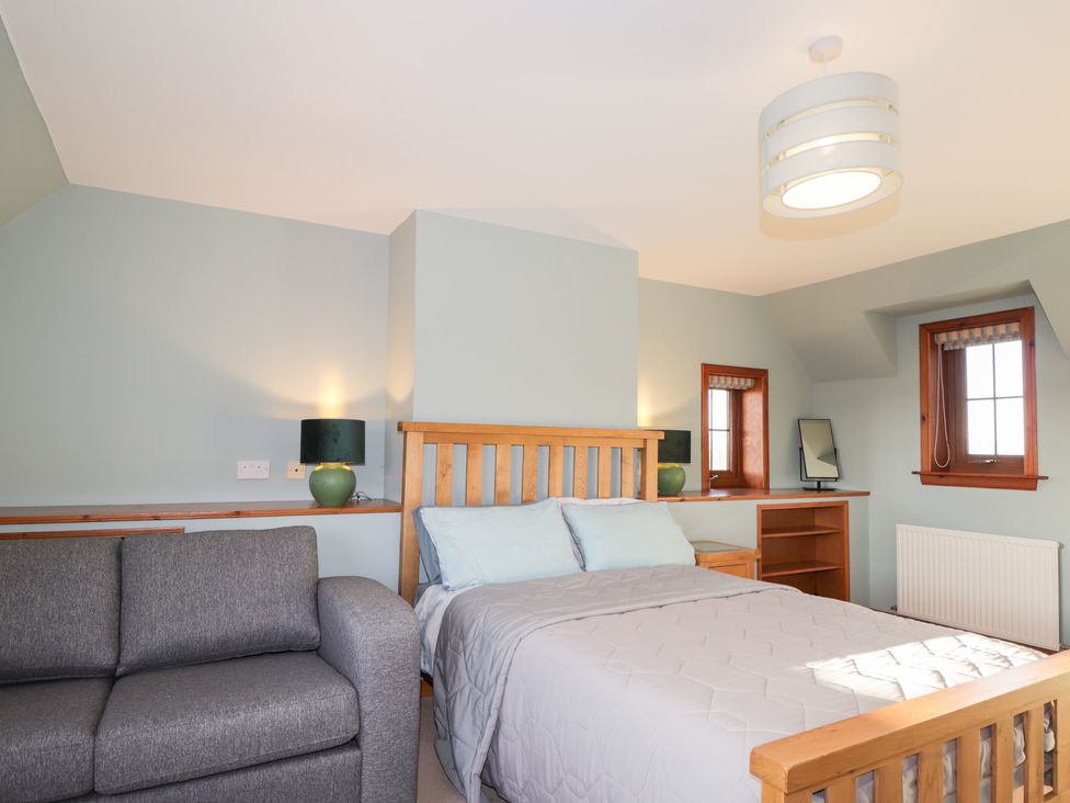 A bedroom with a bed, sofa, lamp, and window at Northbanks House Thurso