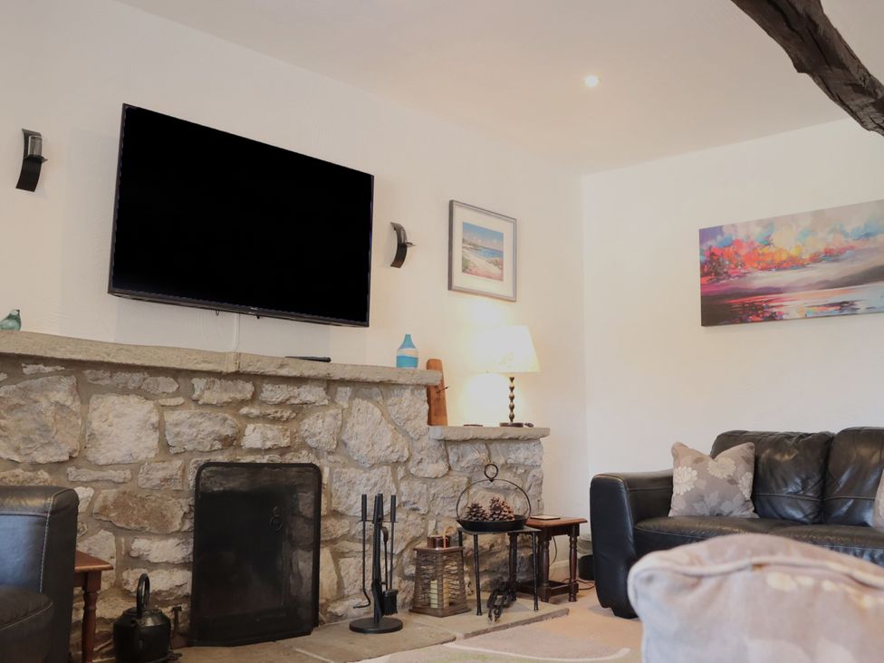 A living room with a tv and a stone fireplace at The Little Farmhouse in Carnforth