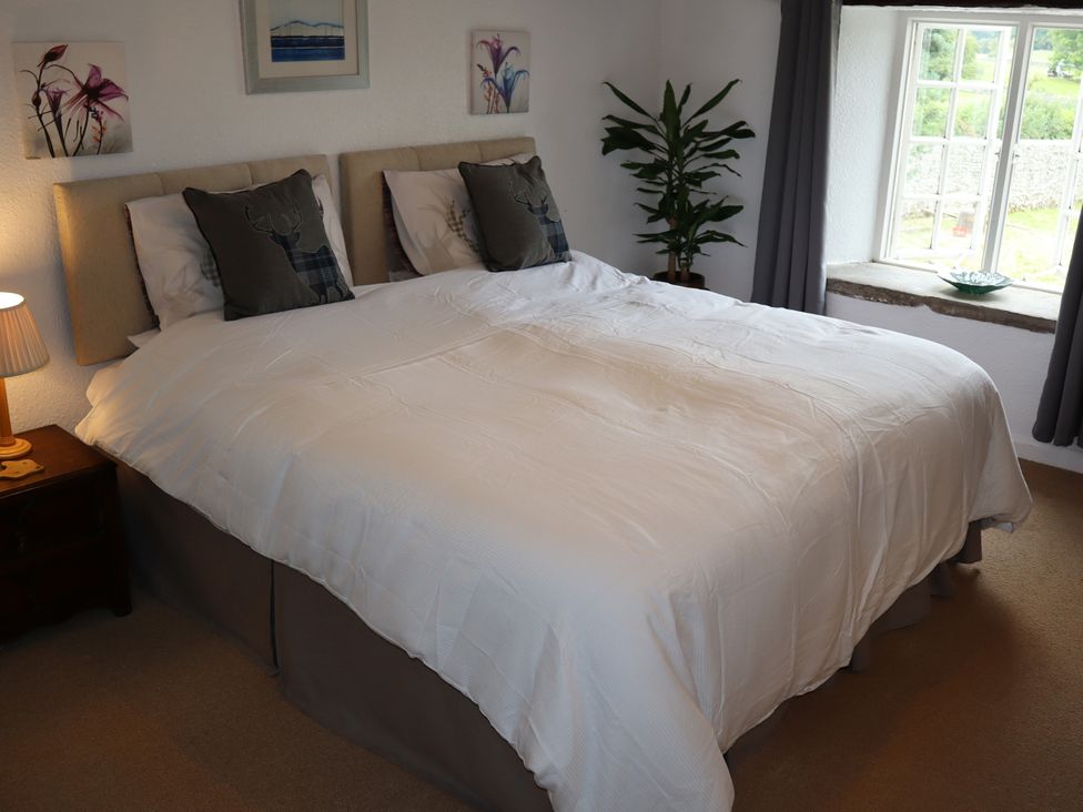 A bedroom with a large bed and a window at The Little Farmhouse in Carnforth