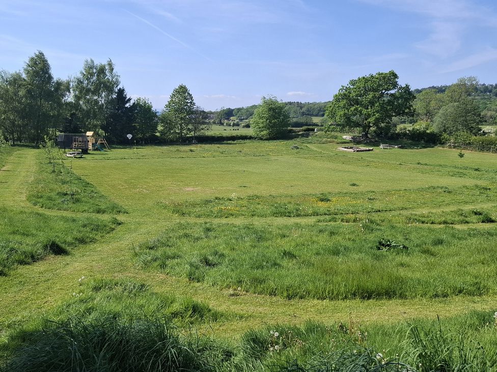 An outdoor area with grass, a playground, trees and a seating area at The Little Farmhouse in Carnforth