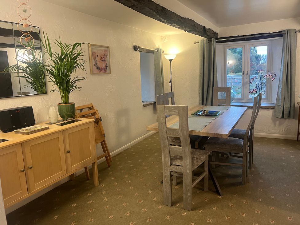 A dining room with a table, chairs, and a cabinet at The Old Farmhouse at Brackenthwaite Farm Yealand Redmayne near Arnside