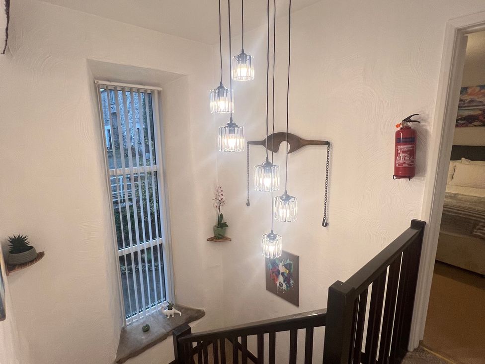 A staircase with light fixtures and wall art at The Old Farmhouse at Brackenthwaite Farm Yealand Redmayne near Arnside