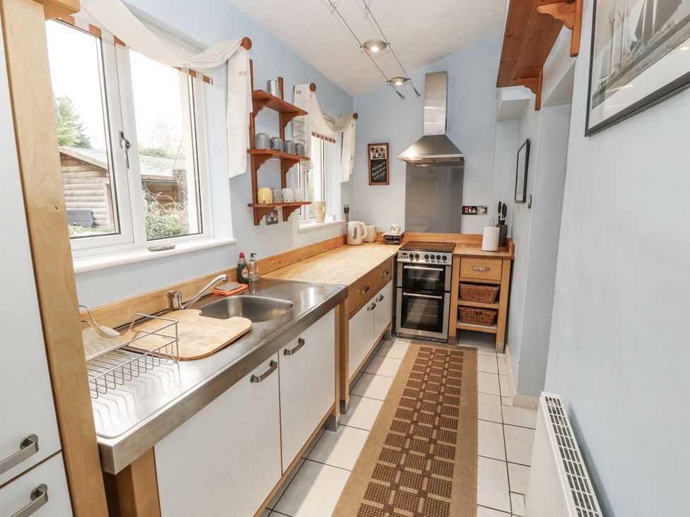 A kitchen with a countertop, sink, oven and shelves at 2 Bens Row Backbarrow near Newby Bridge