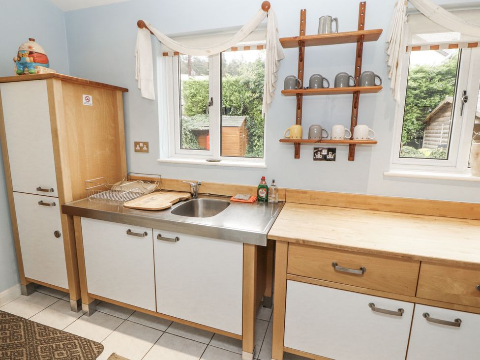 A kitchen with a sink and shelves holding mugs at 2 Bens Row Backbarrow near Newby Bridge
