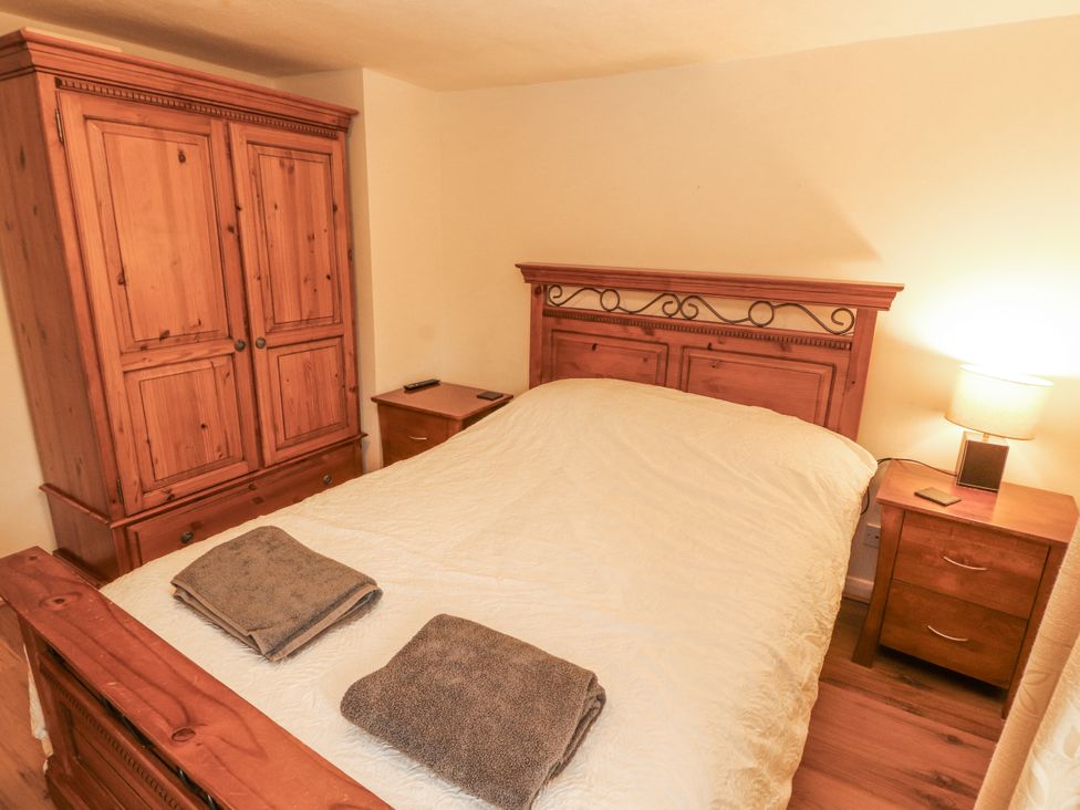 A bedroom with a bed, wardrobe, and bedside table at 2 Bens Row Backbarrow near Newby Bridge