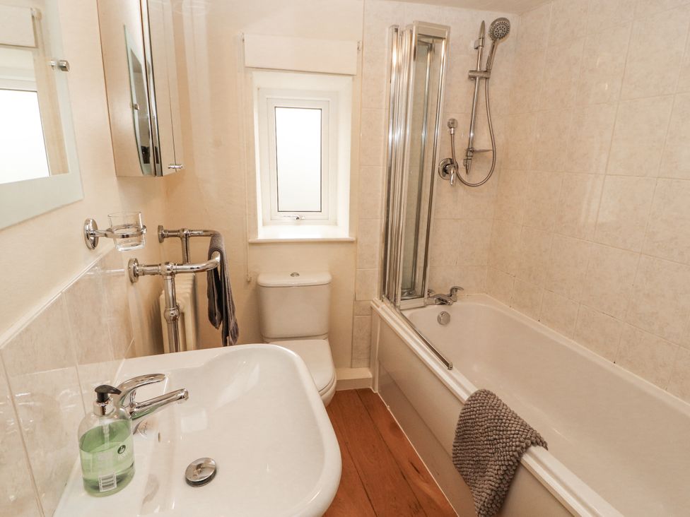 A bathroom with a bathtub, shower, toilet, and sink at 2 Bens Row Backbarrow near Newby Bridge
