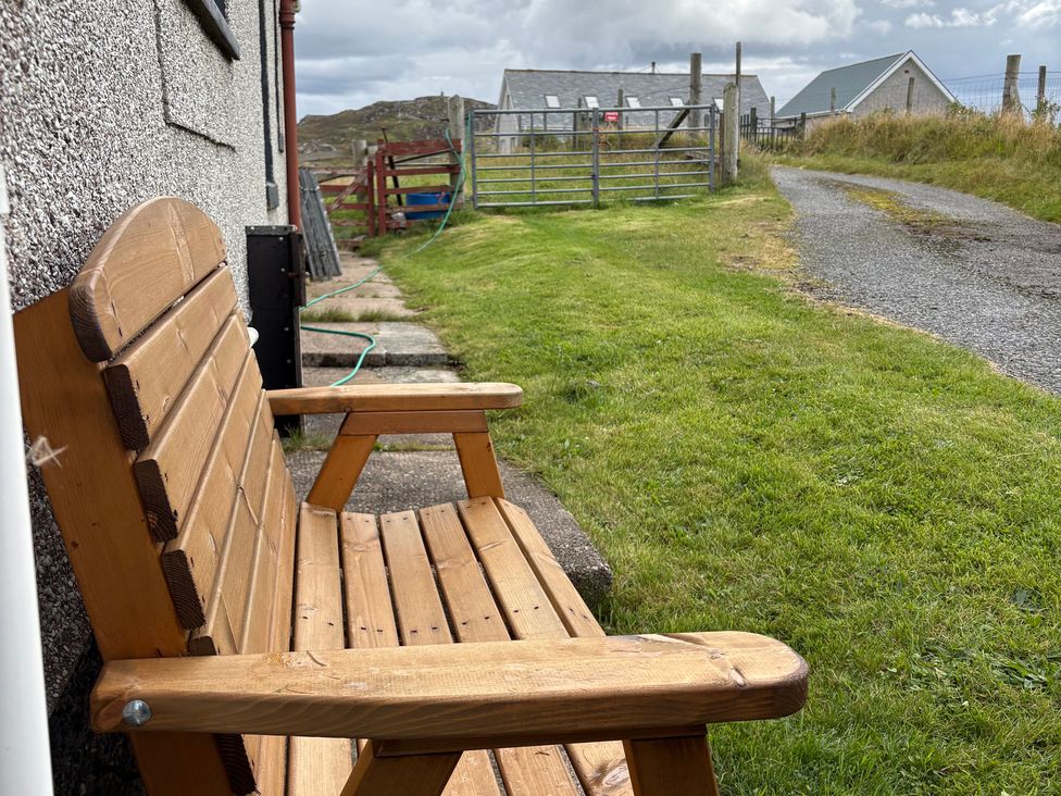 A bench next to a grassy area leading to a gate at 11 Knock in Carloway