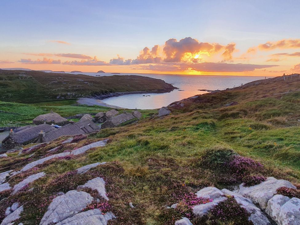A landscape view of a sunset over the ocean at 11 Knock in Carloway
