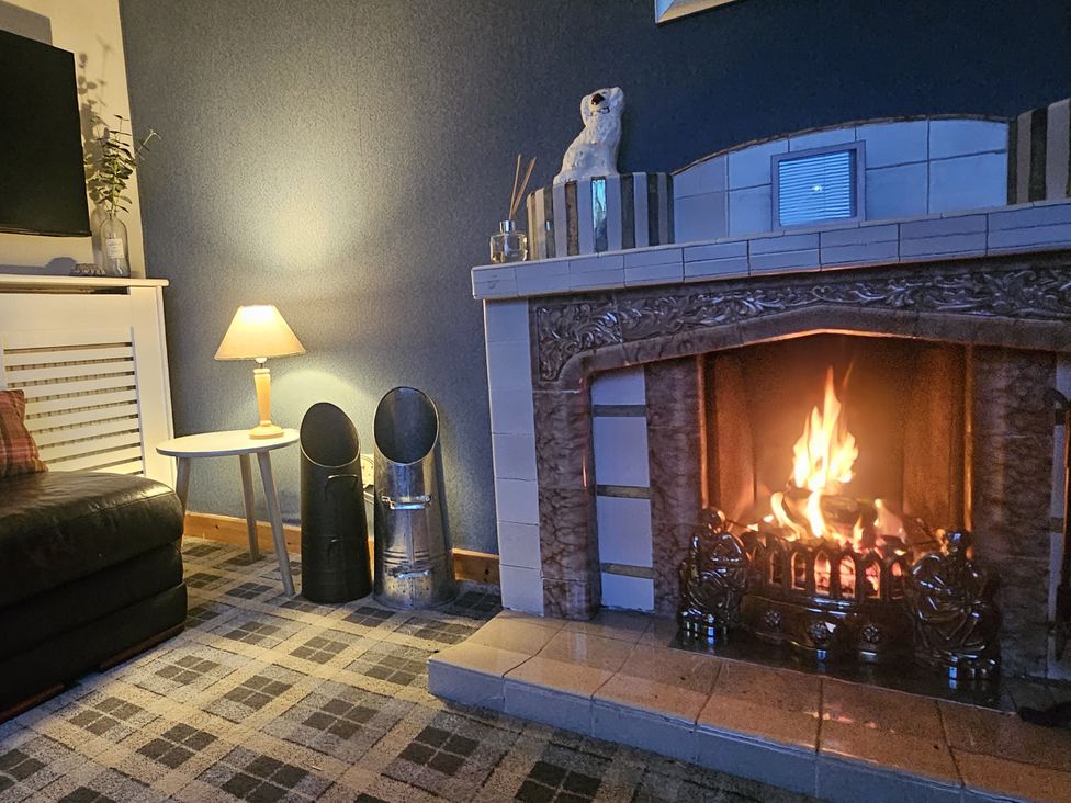 A living room with a fireplace and a sofa at 11 Knock in Carloway