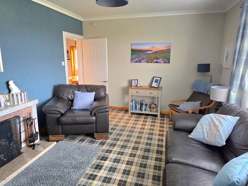 A living room with furniture including a sofa and armchair at 11 Knock in Carloway