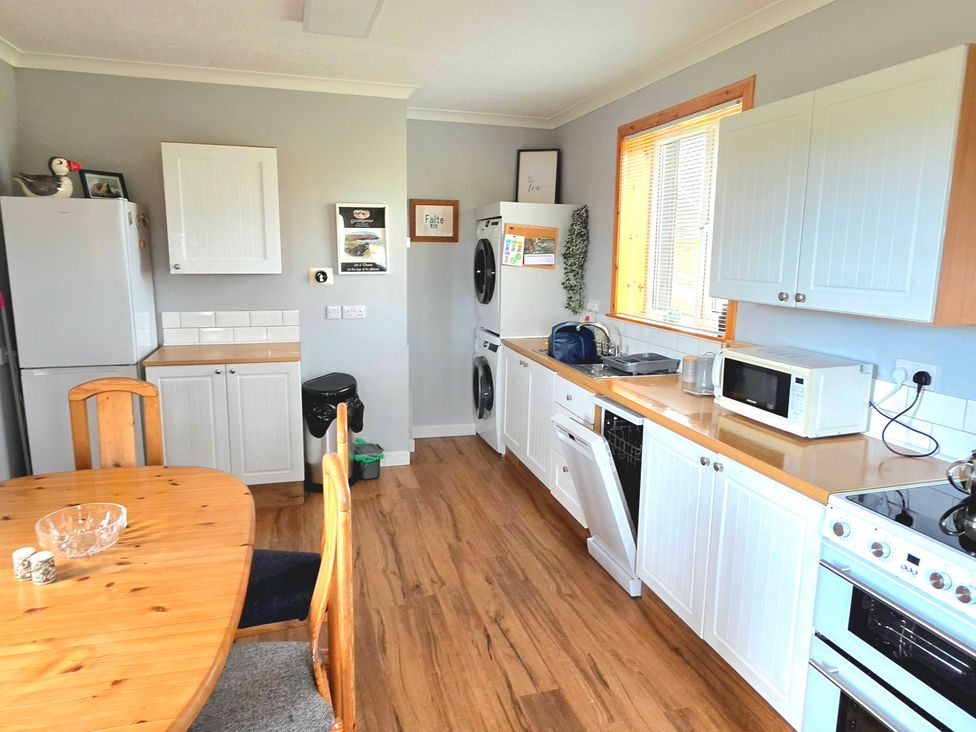 A kitchen with appliances and a dining table at 11 Knock in Carloway