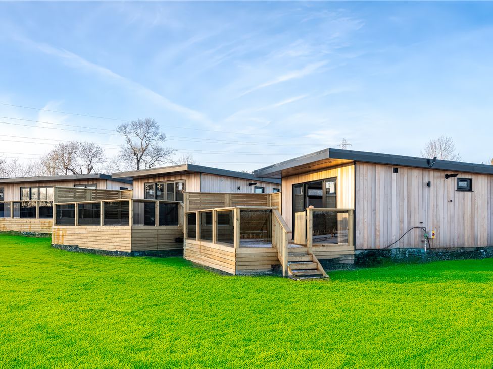 Wooden houses with decks on a green lawn at Dove Lodge in Yarm